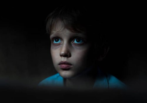 Sad boy sitting in dark room