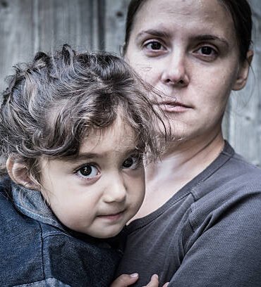 A woman holds a child, trying to calm him down. The child is three years.